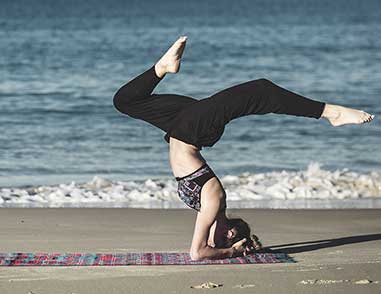 Девушка занимается йогой на берегу моря